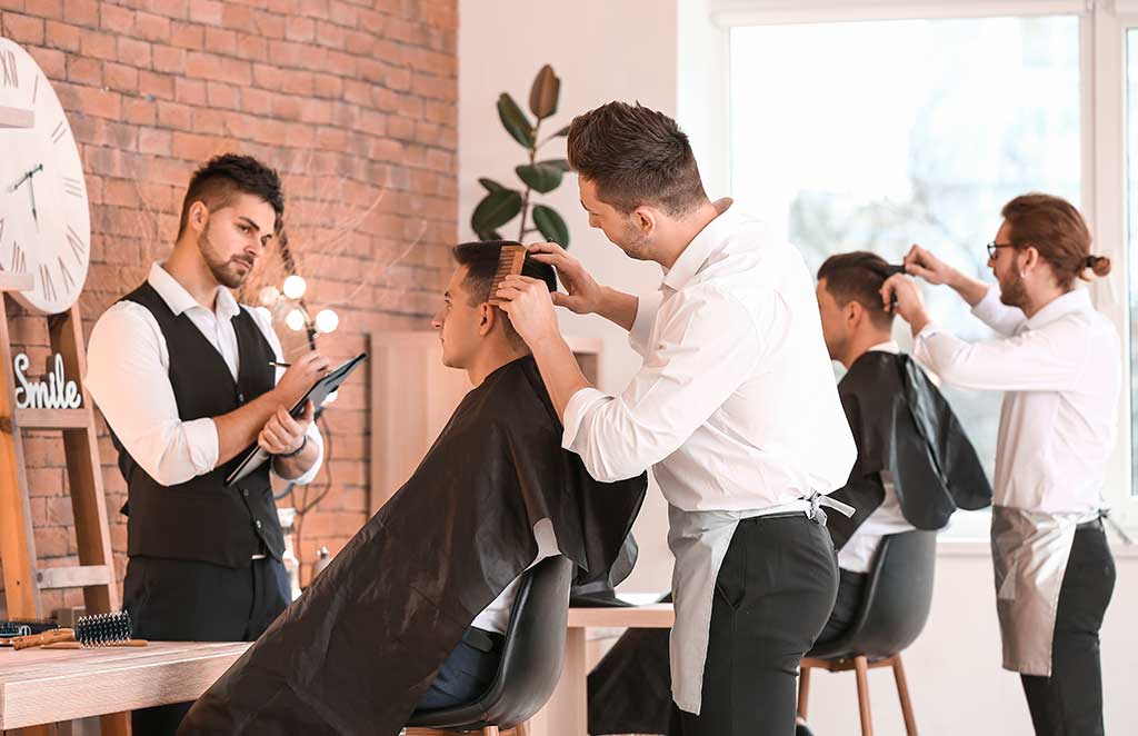 Young men with professional hairdresser during courses in salon